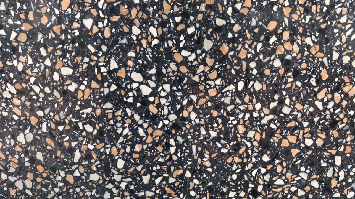 •Close-up of Amber Night terrazzo with charcoal matrix and irregular white grey and amber chips